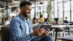 Homme souriant utilisant une tablette au bureau.